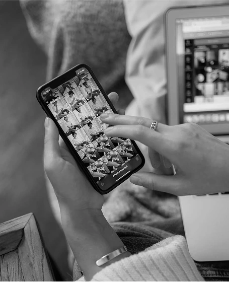 Женская рука листает галерею с личными фото на смартфоне, рядом открыт ноутбук.